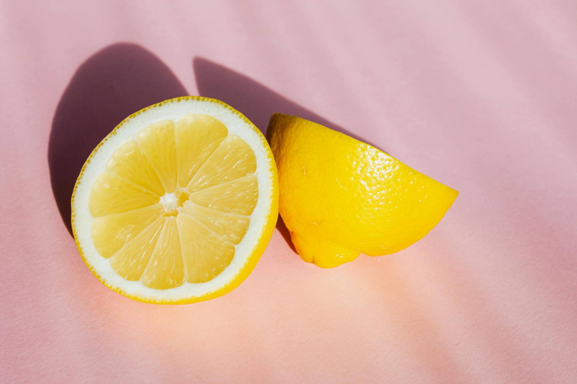 Fresh lemons in natural sunlight on a pink background