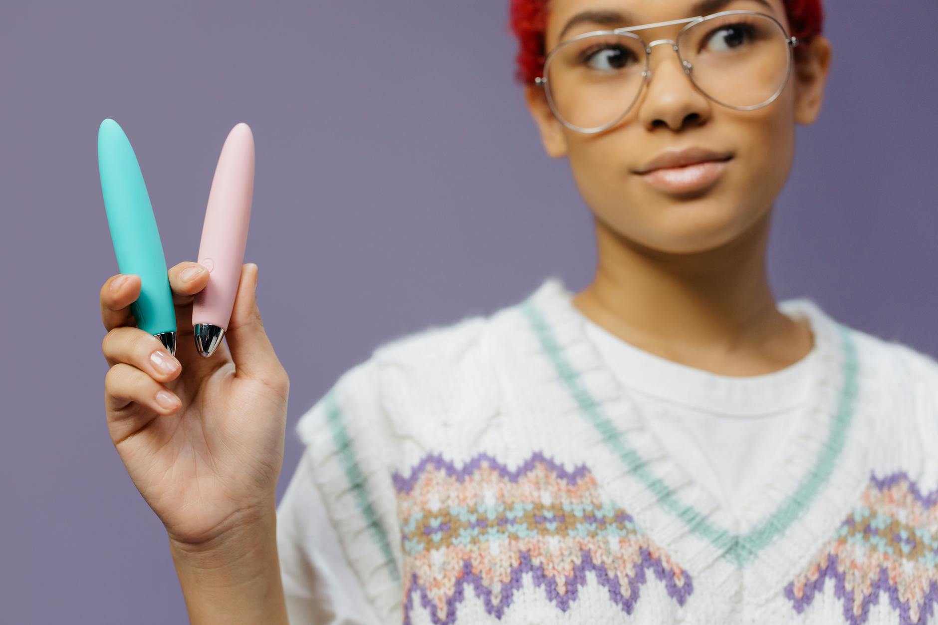 A woman holding a vibrator against a purple background, representing confidence and self-pleasure