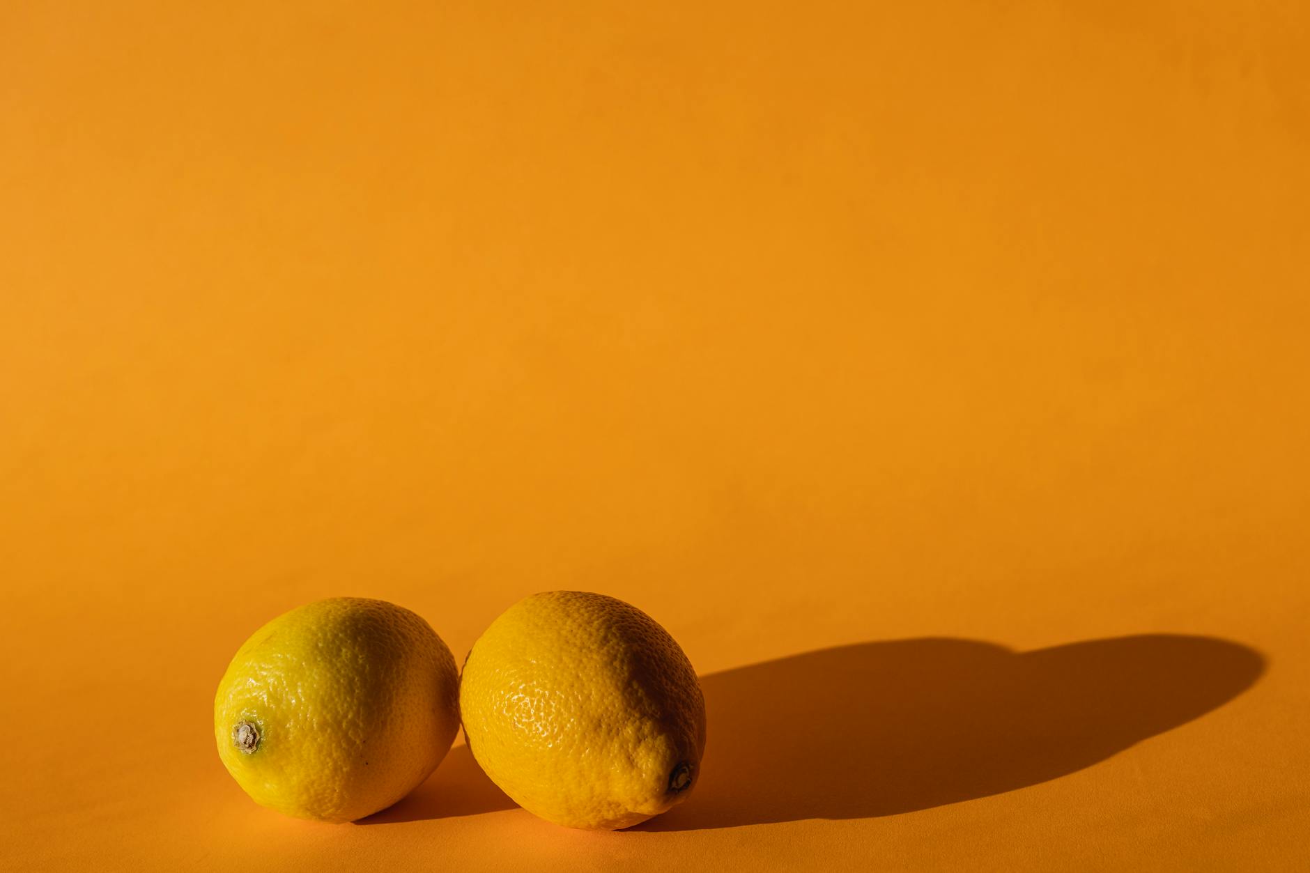 Bright ripe lemons arranged on a yellow background in sunlight